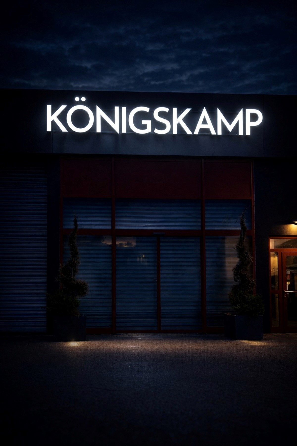 Front-lit svjetleća slova „KÖNIGSKAMP“ na fasadi objekta noću